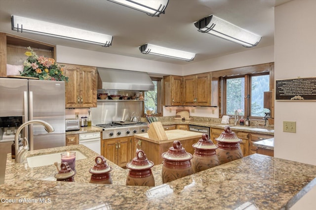2885 S Folsom Ridge Rd, Coeur Dalene, ID 83814 - kitchen with wall chimney range hood, stainless steel appliances, brown cabinetry, a center island, and a sink