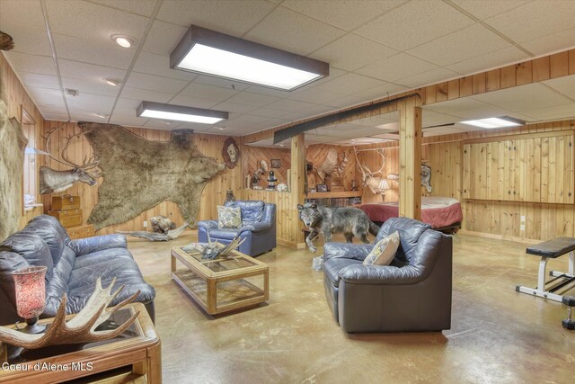 2885 S Folsom Ridge Rd, Coeur Dalene, ID 83814 - living room featuring wooden walls, concrete flooring, a paneled ceiling, and baseboards