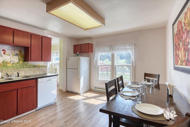 2885 S Folsom Ridge Rd, Coeur Dalene, ID 83814 - kitchen with white appliances, a sink, light wood-style flooring, decorative backsplash, and baseboard heating
