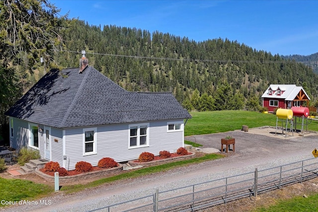 2885 S Folsom Ridge Rd, Coeur Dalene, ID 83814 - view of home's exterior with a wooded view, a chimney, and a shingled roof