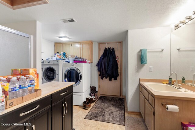 laundry room with a sink, separate washer and dryer, a textured ceiling, and cabinet space