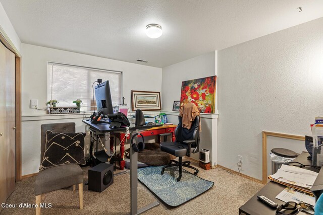 office area featuring baseboards, visible vents, a textured wall, and carpet