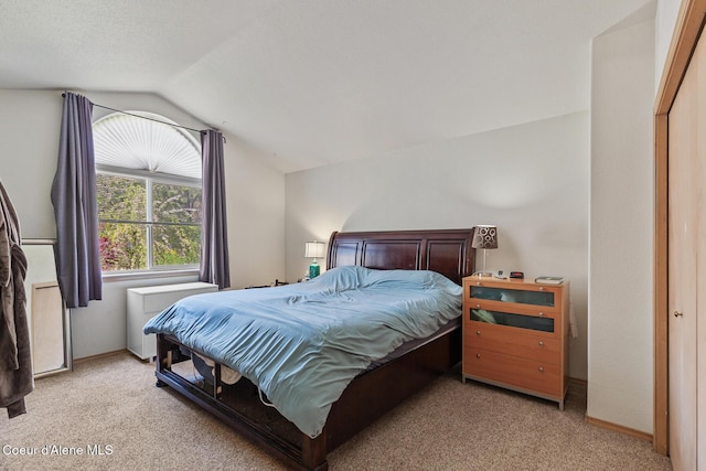 bedroom featuring baseboards, lofted ceiling, and light carpet