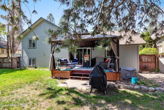rear view of property featuring an outdoor living space, fence, a yard, and a deck