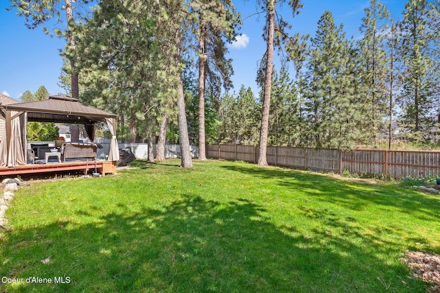 view of yard with a gazebo, a wooden deck, and a fenced backyard