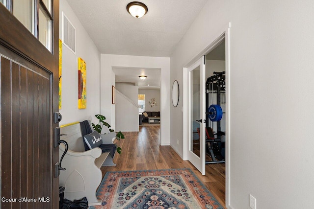 foyer with wood finished floors, french doors, and visible vents