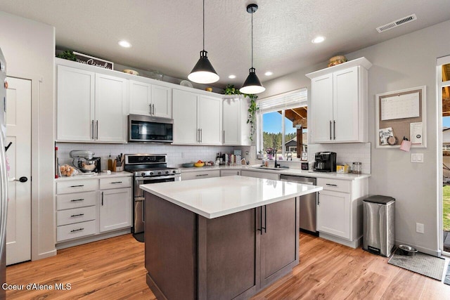 kitchen with tasteful backsplash, appliances with stainless steel finishes, a sink, white cabinetry, and visible vents