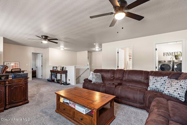 living area featuring a ceiling fan, a textured ceiling, carpet floors, and washer and clothes dryer