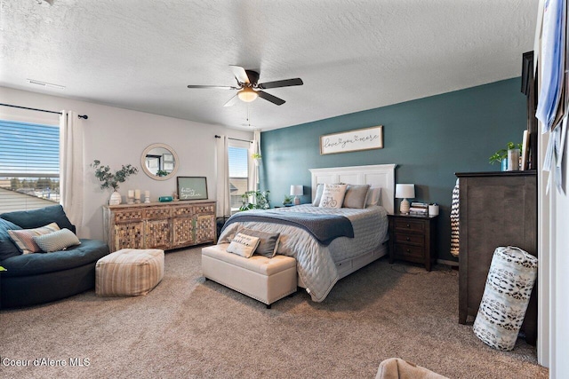 carpeted bedroom with a textured ceiling, visible vents, and a ceiling fan