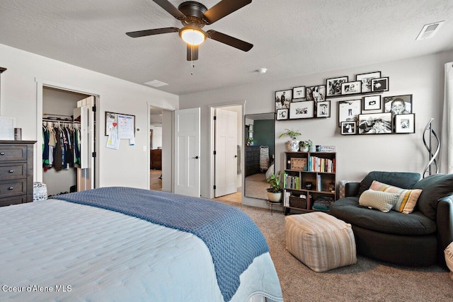 bedroom featuring a spacious closet, ceiling fan, a textured ceiling, and carpet flooring