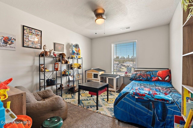 carpeted bedroom featuring a textured ceiling, visible vents, and a ceiling fan