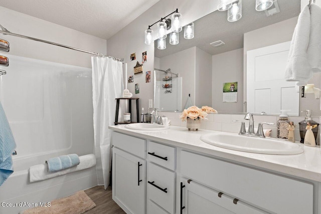 bathroom with double vanity, shower / tub combo with curtain, wood finished floors, and a sink