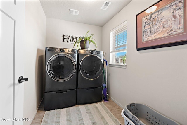 washroom with visible vents, baseboards, separate washer and dryer, wood finished floors, and laundry area