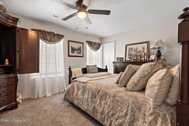 bedroom with visible vents, a ceiling fan, light carpet, and a textured ceiling