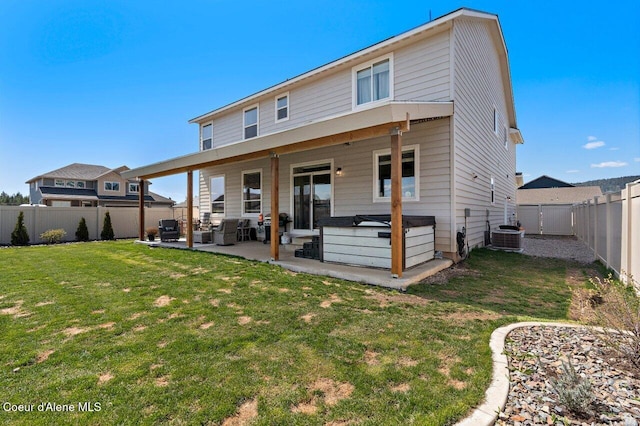 back of property featuring a yard, a patio area, a hot tub, and a fenced backyard