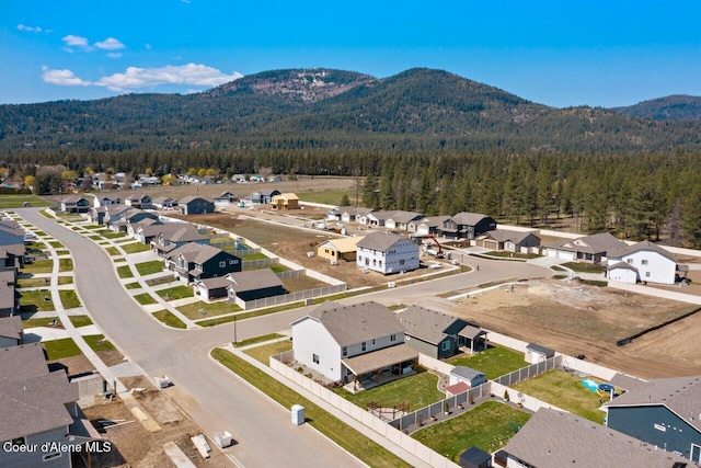 birds eye view of property with a wooded view, a mountain view, and a residential view