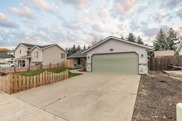 ranch-style home with fence, a front yard, concrete driveway, and stone siding