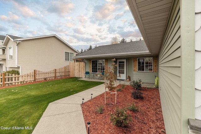 view of front of home featuring fence, roof with shingles, and a front yard