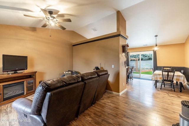 living area with ceiling fan, vaulted ceiling, wood finished floors, and baseboards