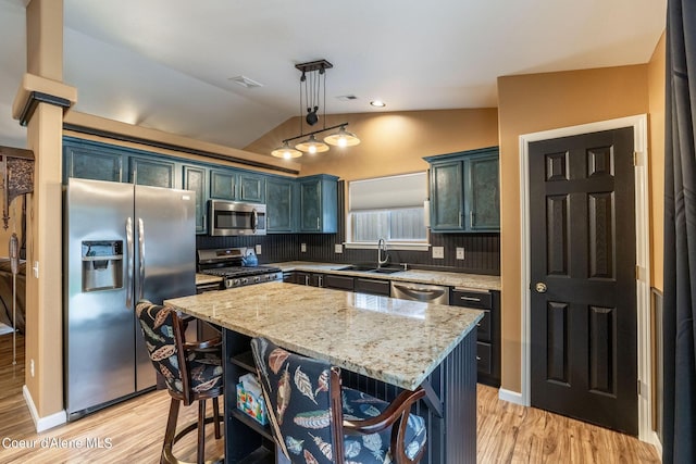 kitchen with stainless steel appliances, a sink, light wood-style flooring, and vaulted ceiling