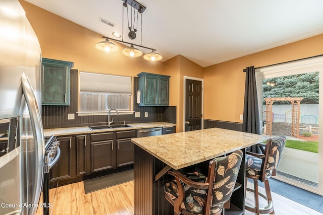 kitchen with a sink, light wood-style flooring, stainless steel appliances, and visible vents