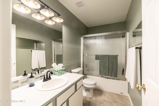 full bath featuring toilet, combined bath / shower with glass door, visible vents, and vanity