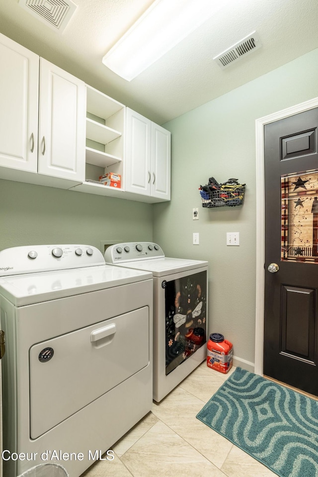 washroom with light tile patterned floors, separate washer and dryer, cabinet space, and visible vents