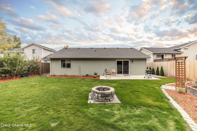 back of property featuring a lawn, a fire pit, a fenced backyard, and a patio area