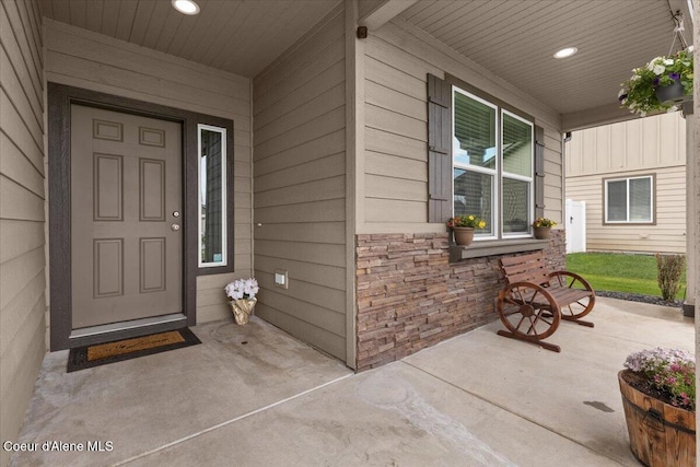 doorway to property with a porch and stone siding