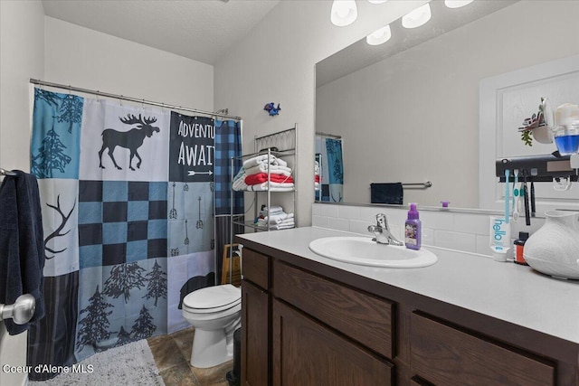 full bathroom featuring vanity, toilet, stone finish flooring, decorative backsplash, and curtained shower