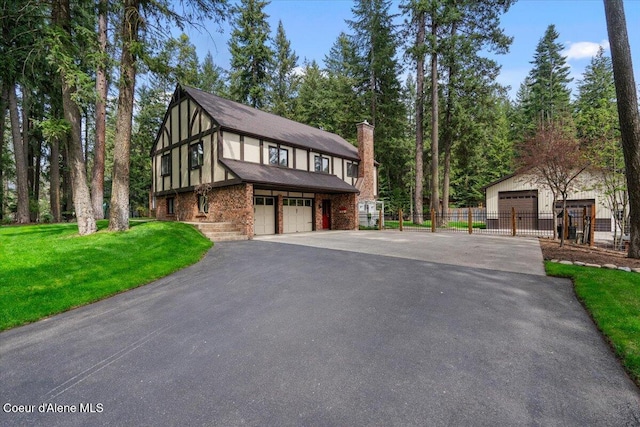 english style home featuring fence, a chimney, and a front lawn