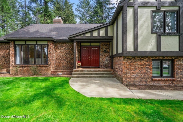 view of front of home featuring brick siding, a chimney, a front yard, and roof with shingles