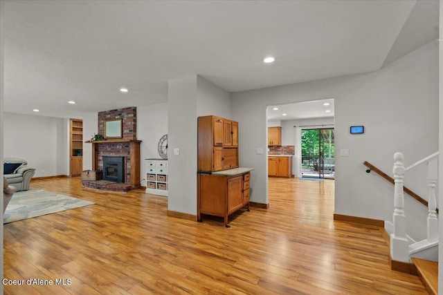 living room featuring light wood finished floors, a brick fireplace, recessed lighting, baseboards, and stairway