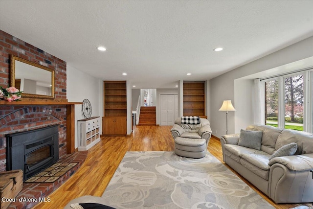 living room featuring light wood-style floors, a textured ceiling, stairs, and recessed lighting