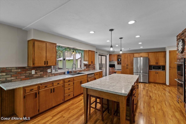 kitchen with brown cabinets, a sink, light countertops, stainless steel appliances, and recessed lighting