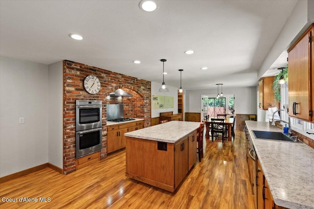 kitchen with a kitchen island, gas stovetop, a sink, double oven, and light wood finished floors