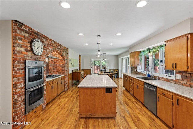 kitchen featuring light wood-type flooring, a sink, appliances with stainless steel finishes, and a kitchen island