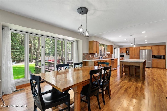 dining space featuring plenty of natural light, light wood-style flooring, and visible vents