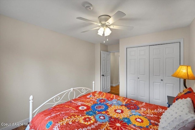 bedroom with baseboards, ceiling fan, a closet, and wood finished floors