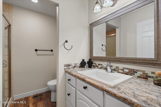 bathroom featuring wood finished floors, backsplash, and a shower stall