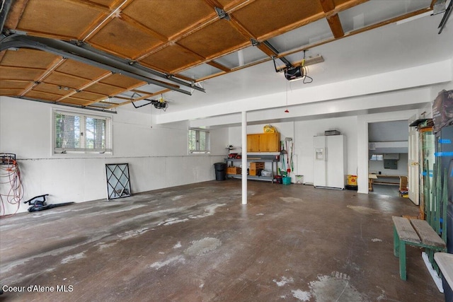 garage featuring a garage door opener and white refrigerator with ice dispenser