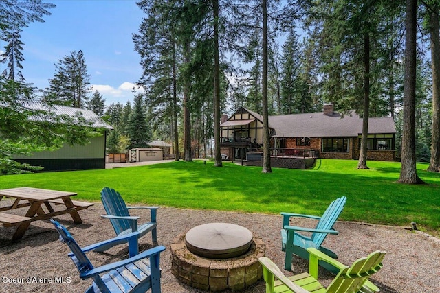 view of yard featuring an outdoor structure, an outdoor fire pit, a shed, and a deck