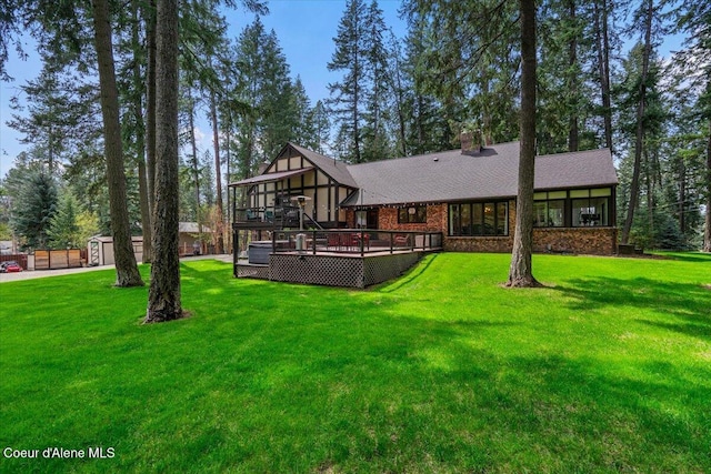 back of house featuring a lawn, a storage unit, an outdoor structure, and a deck