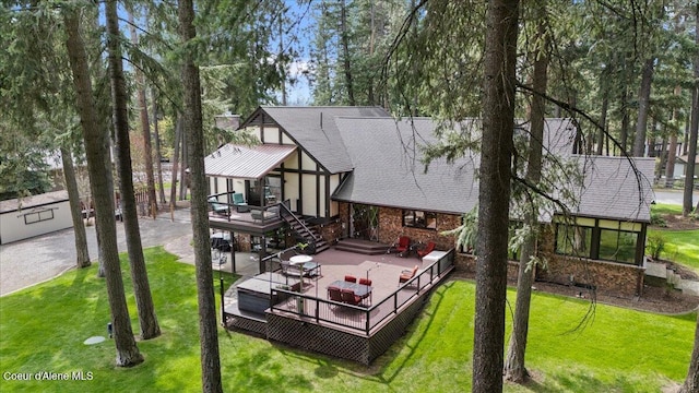 back of property with a lawn, a shingled roof, a deck, and brick siding