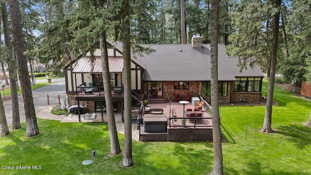 back of property with roof with shingles, a chimney, a yard, and a deck