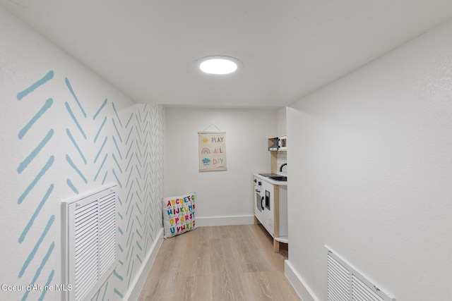 interior space featuring visible vents, light wood-type flooring, a sink, and baseboards