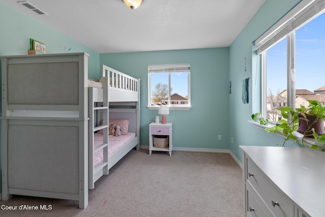 bedroom with baseboards, visible vents, and light colored carpet