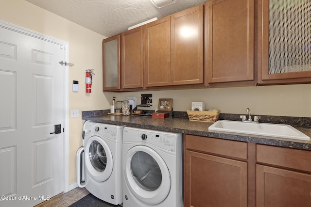 laundry room featuring a textured ceiling, a sink, baseboards, washer and clothes dryer, and cabinet space