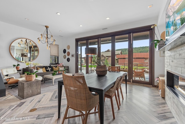dining room with a wealth of natural light, a glass covered fireplace, french doors, and a notable chandelier