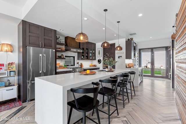 kitchen featuring recessed lighting, high end fridge, dark brown cabinetry, and light countertops